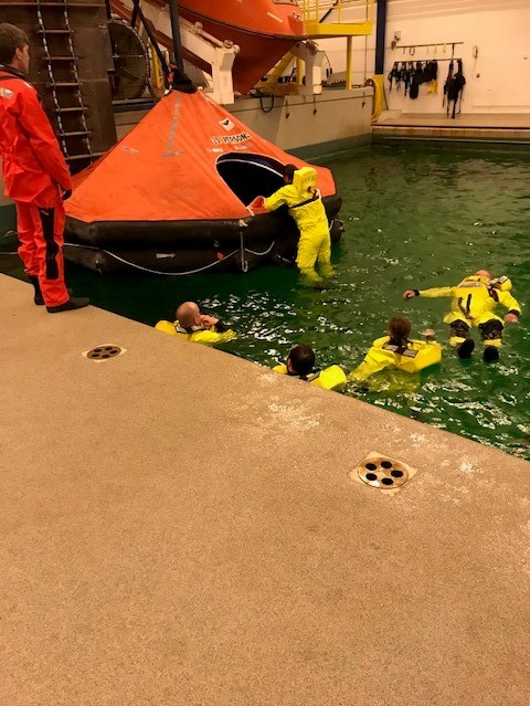 5 personer i gule dragter træner i en bassin